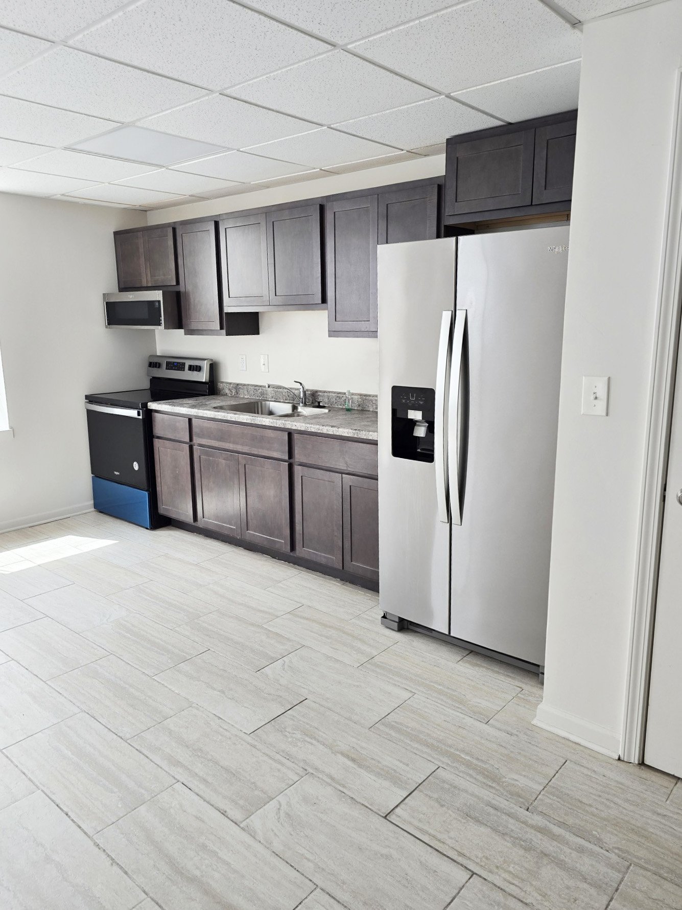 A kitchen with a white fridge and a black microwave.